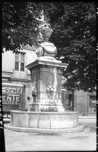 Fontaine sur une place, devantures de boutiques