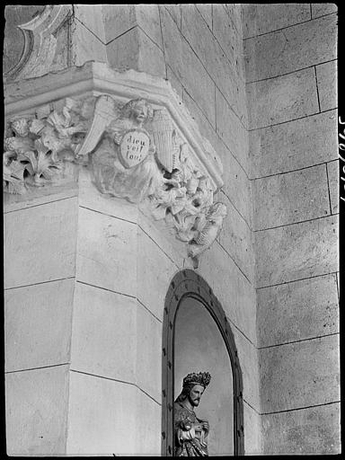 Intérieur : chapiteau avec inscription et personnages, statue dans une niche