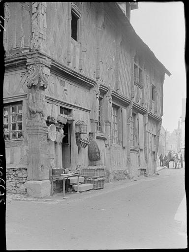 Façade sur rue décorée de paniers d'osier, poteau-cornier sculpté