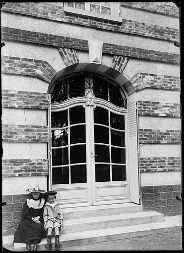 Porte d'entrée, enfants assis sur l'escalier extérieur
