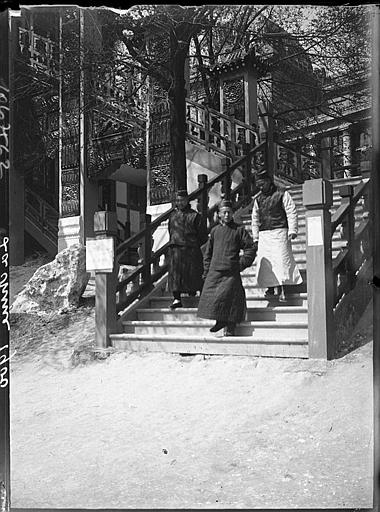 Trois hommes en costume traditionnel chinois sur un escalier