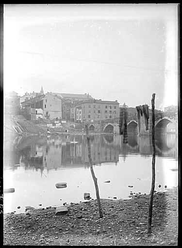 Aux bords du fleuve, épandage de linge, immeubles à l'arrière-plan