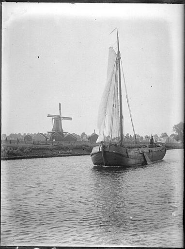 Voilier sur le canal devant un moulin à vent