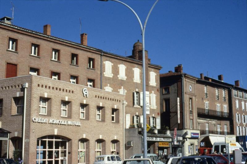 Place du Vigan : devantures de commerces et constructions empiétant sur la place