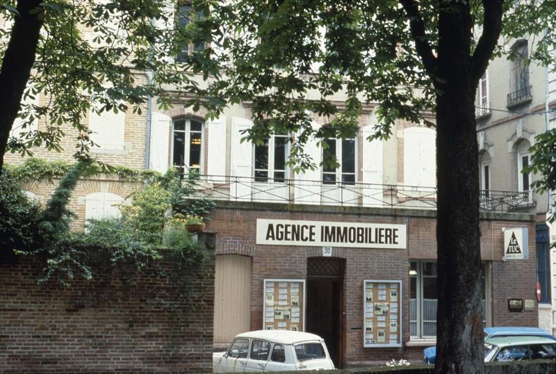 Rue du Docteur-Laurent-Camboulives : façade d'immeuble et devanture d'une agence immobilière