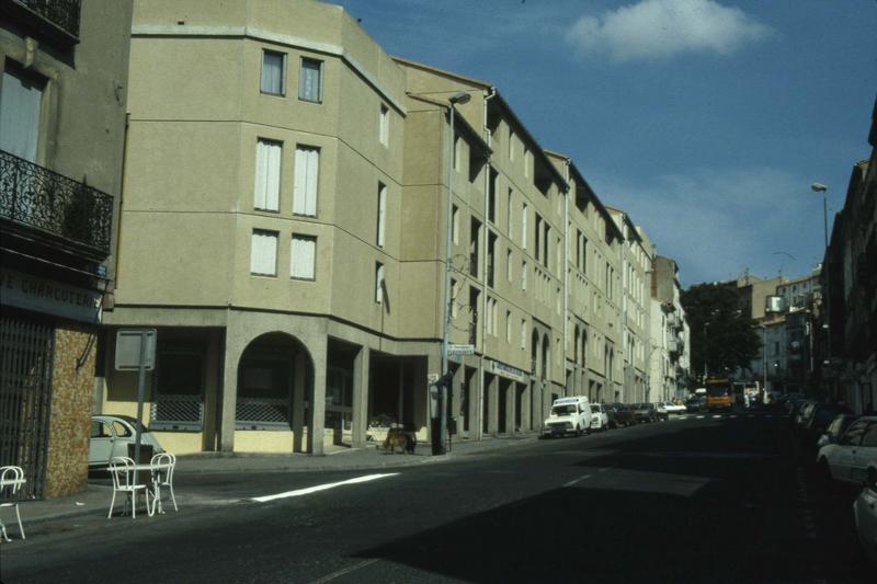 Rue bordée d'immeubles modernes d'un côté et d'immeubles anciens de l'autre