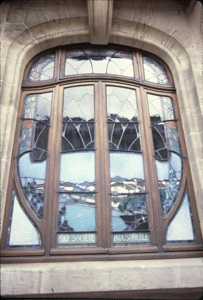 Fenêtre du rez-de-chaussée sur rue avec vitrail