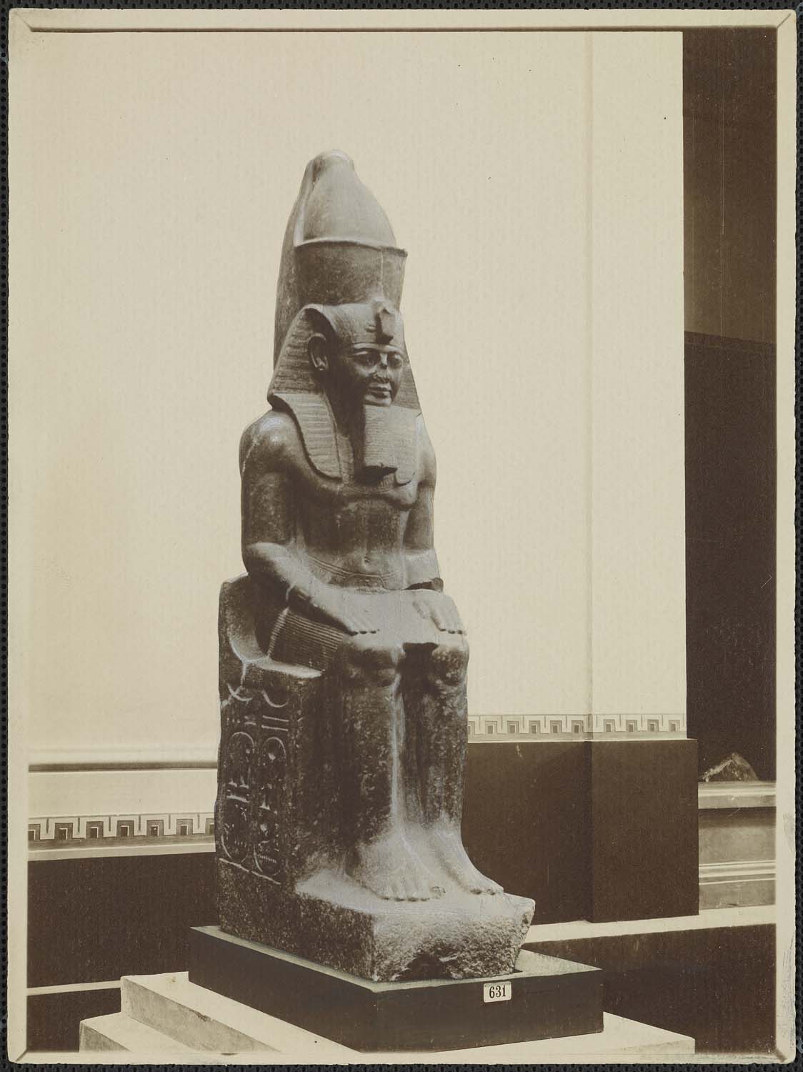 Statue de Ramsès II assis sur un trône cubique, coiffé du némès et de la double couronne de Haute et Basse Égypte, granit gris, 19e dynastie, provenant de Tanis