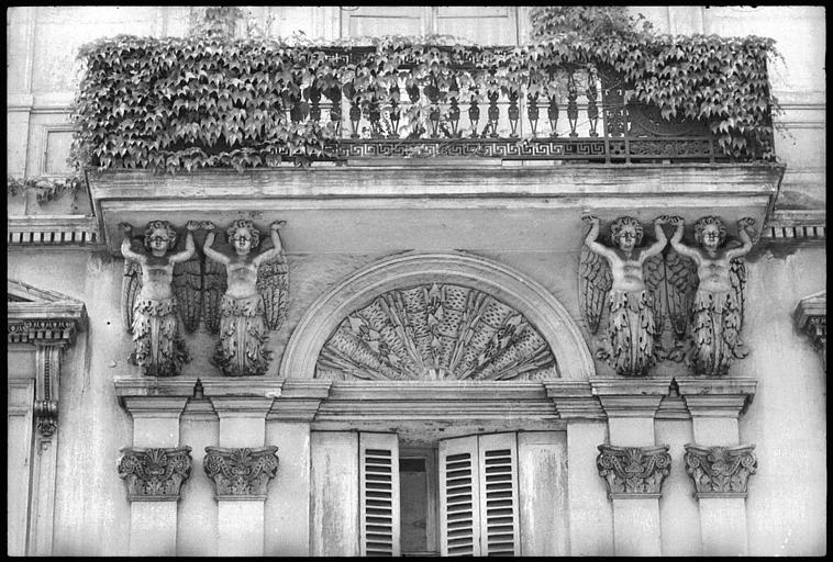 Façade ornée de deux paires d'atlantes ailés en gaine avec bras : vue rapprochée des atlantes