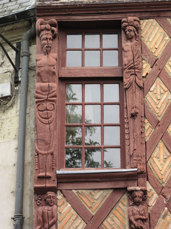 Façade sur la place : fenêtre encadrée de deux figures sculptées