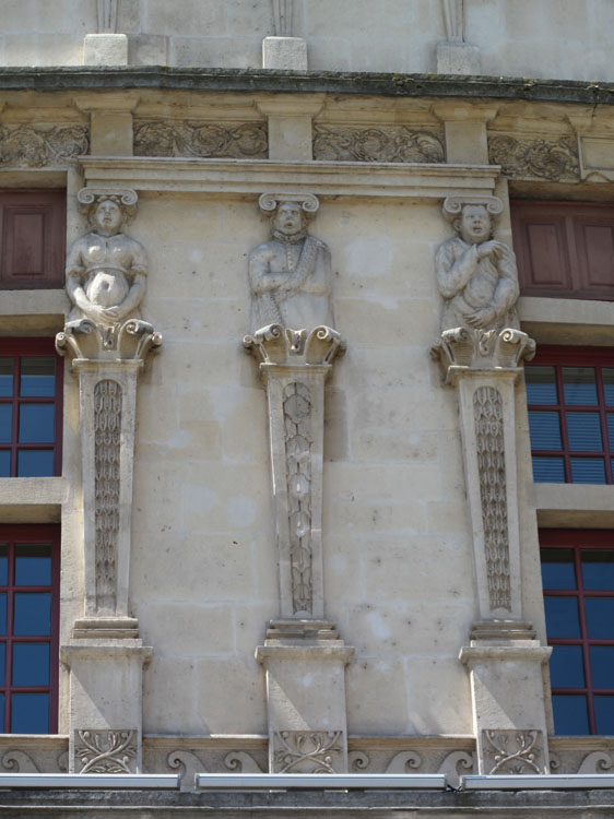 Façade sur la place : pilastres surmontés de figures sculptées entre deux fenêtres