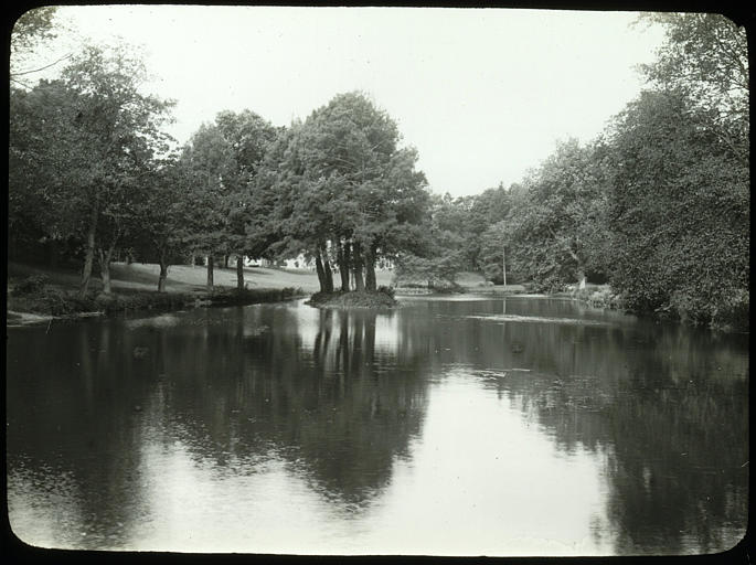 Plan d'eau, végétation, édifice à l'arrière-plan