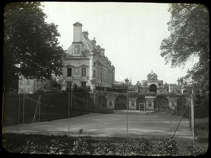 Intérieur, vue d'ensemble, bâtiment et portail à l'arrière-plan, court de tennis au premier plan (supposé)