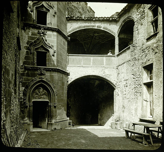 Vue prise à l'intérieur de la cour du château, tourelle d'escalier, une femme apparaissant à la galerie-haute