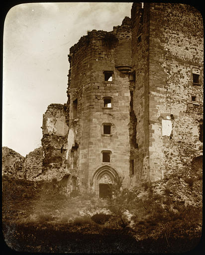 Vue partielle prise de l'intérieur du château, une tour percée d'une entrée et de fenêtres, ruines