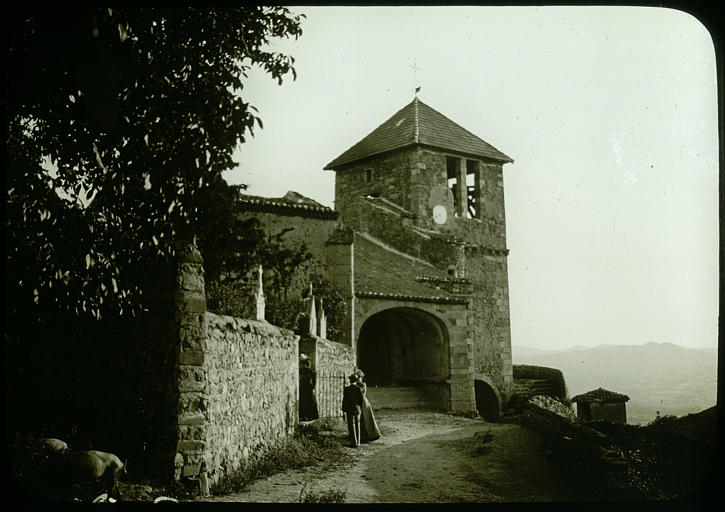 Porche et clocher, mur du cimetière, personnages à la porte du cimetière, panorama à l'arrière-plan