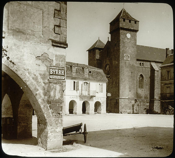 Vue partielle de la place avec des maisons à couverts, église côté sud-ouest avec vue sur le clocher fortifié