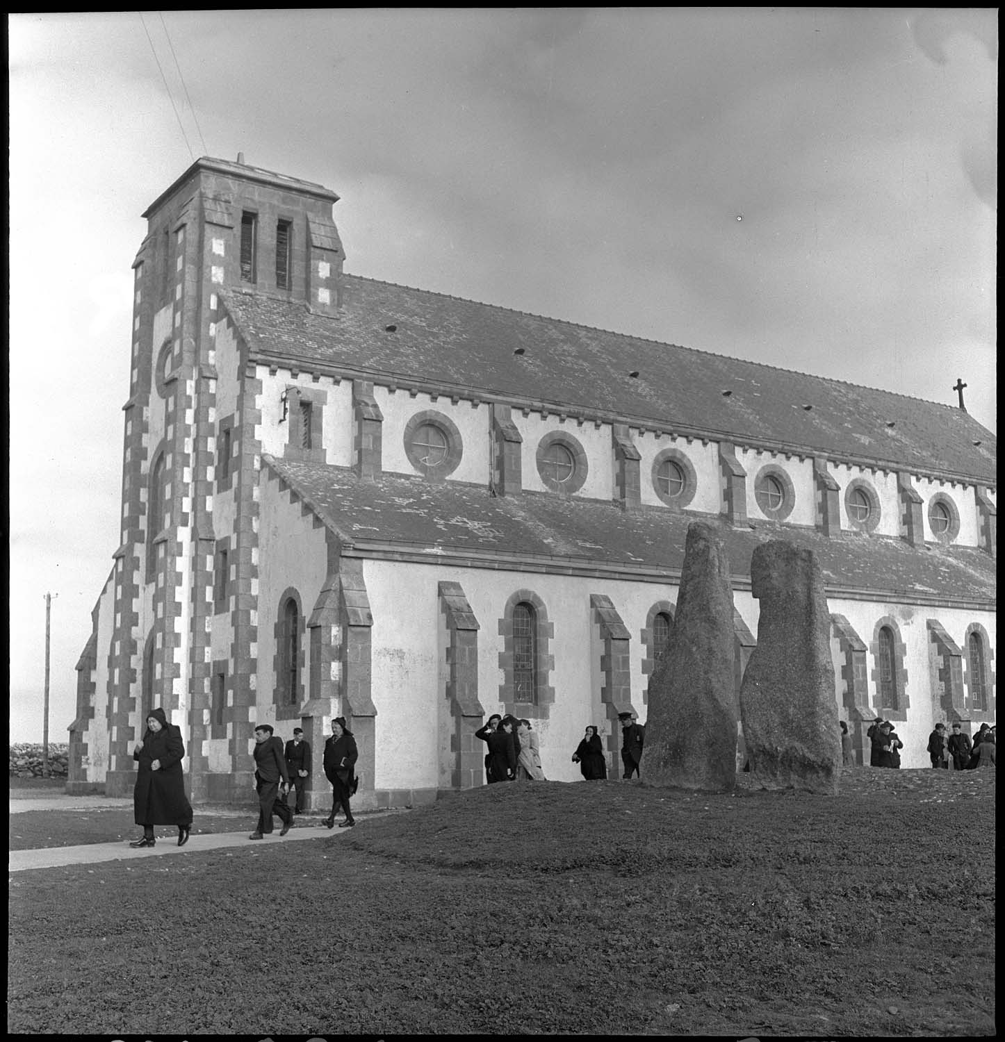 Sortie d’office à l’église paroissiale : fidèles et menhirs