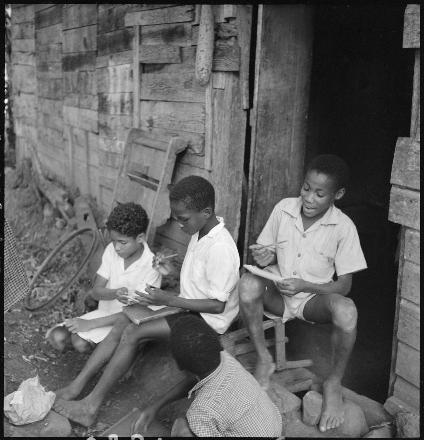 Écoliers faisant leurs devoirs sur le seuil d’une maison