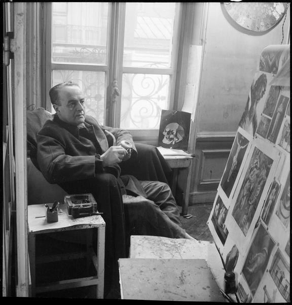 [Portrait de Luis Fernandez Lopez assis dans son atelier regardant un ensemble d'images]