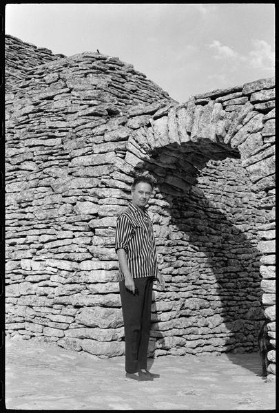 [Portrait de Victor Vasarely devant l'entrée de sa propriété surmontée d'une arche en pierre sèche]