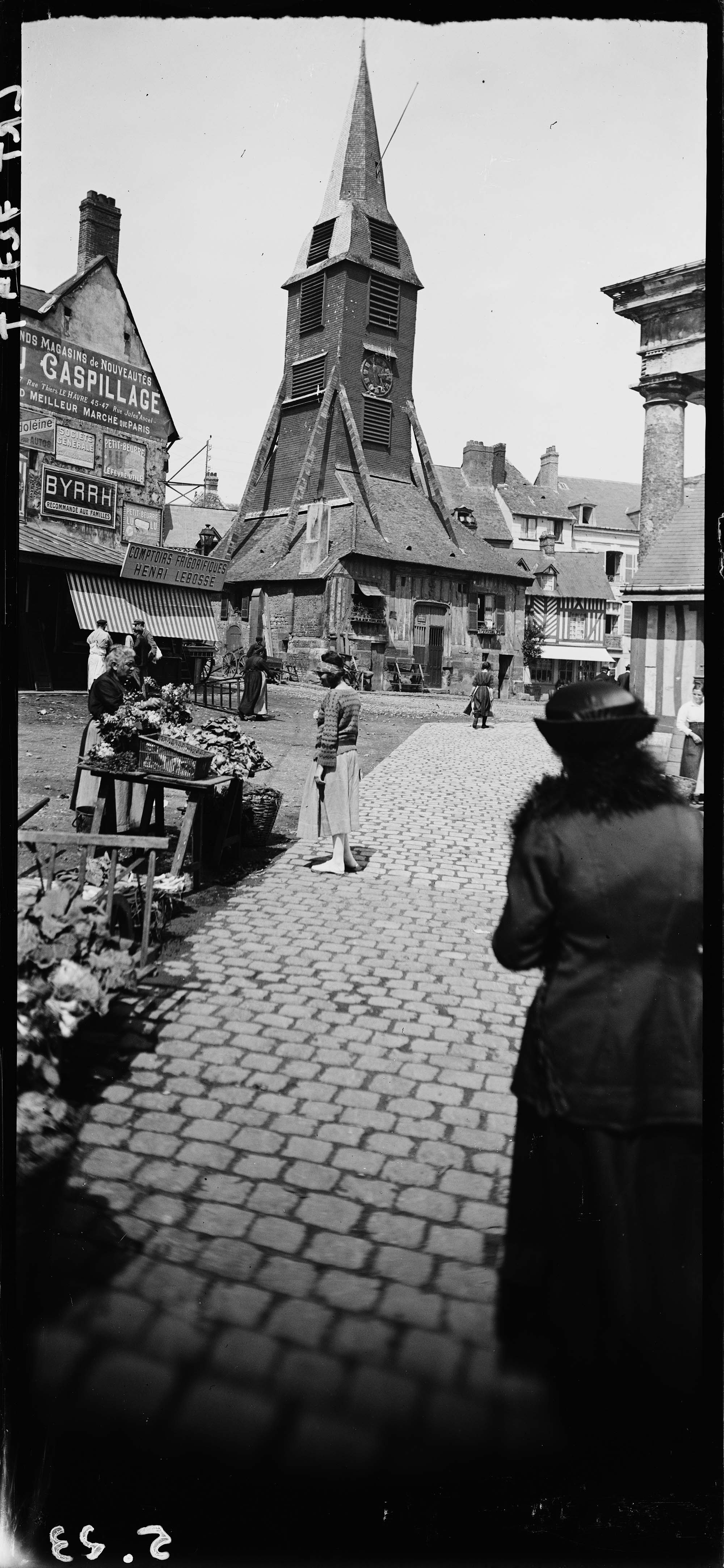 [Juin, Honfleur, Madeleine Messager devant un étal de marché sur la place derrière l'église]