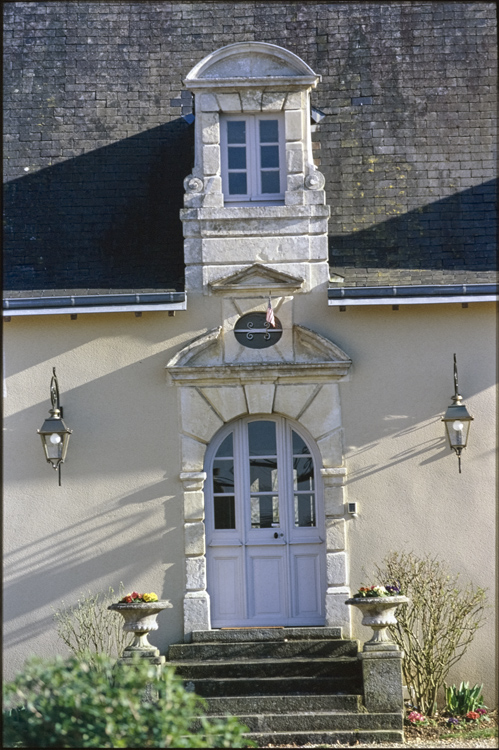 Porte du corps central surmontée d’une lucarne accolée de volutes et couronnée d’un fronton cintré