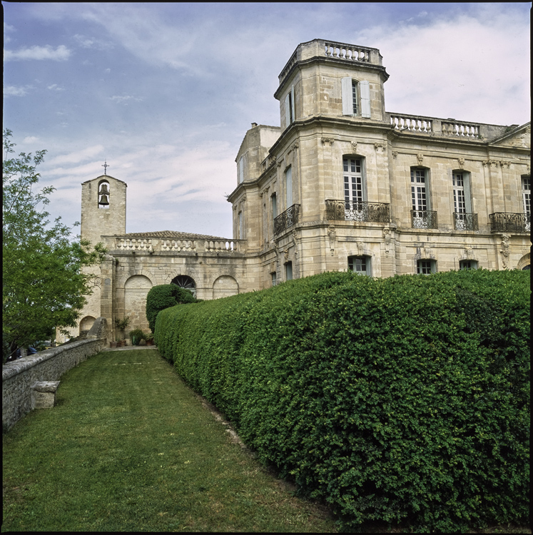 Vue partielle de la façade du château ; Clocher de l’église à l’arrière-plan