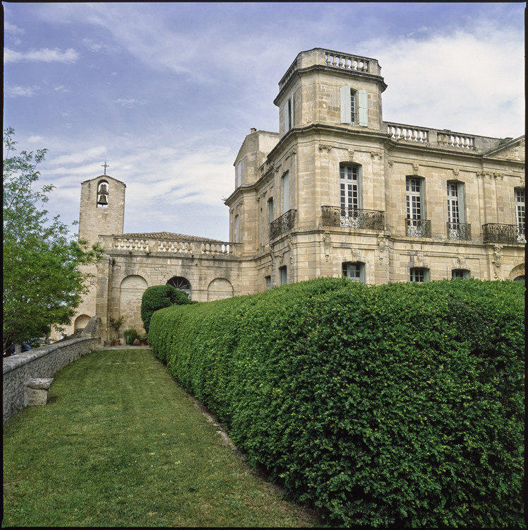 Vue partielle de la façade du château ; Clocher de l’église à l’arrière-plan