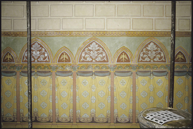 Chapelle des fonds baptismaux, mur ouest ; peinture monumentale : rideaux, colonnes et arcs feints, rinceaux végétaux, phoenix stylisé ; après restauration (détail)