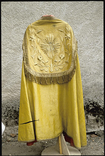 Chape : tissu jaune, galon doré, dos brodé de fleurs de lys, de roses et d'épis de blé, initiales de Marie entrelacées et couronnées