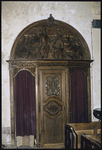 Confessionnal : bois, surmonté d'un fronton cintré décoré d'un bas-relief représentant un roi agenouillé devant un personnage (le Christ ?), encadrés par deux enroulements de palmes, porte centrale ajourée de volutes