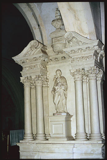 Autel latéral ; retable, groupe sculpté : 'Saint Joseph et l'Enfant', retable architecturé, corniche à modillons et rosaces, frise de fleurs, frise de perles et pirouettes