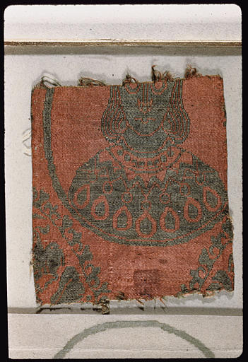 Tissu : fragment, buste de personnage (lacunaire) à cheveux mi-longs, en gris sur fond rouge - © Ministère de la Culture (France), Médiathèque du patrimoine et de la photographie, diffusion RMN-GP