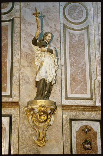 Statue : 'Saint François-Xavier', vêtu en prêtre, brandissant un crucifix de la main droite et tenant sa barrette dans la main gauche, pierre sculptée, peinte