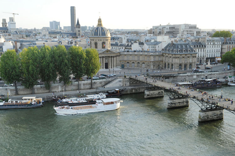 Le pont des Arts et l'Institut depuis le quai François-Mitterrand. Péniches ; église Saint-Germain-des-Prés et tour Montparnasse à l’arrière-plan