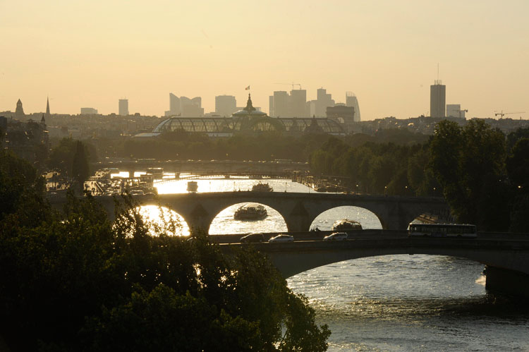 Enfilade de ponts au crépuscule depuis le quai de Conti. À l'arrière-plan, le Grand Palais et la Défense