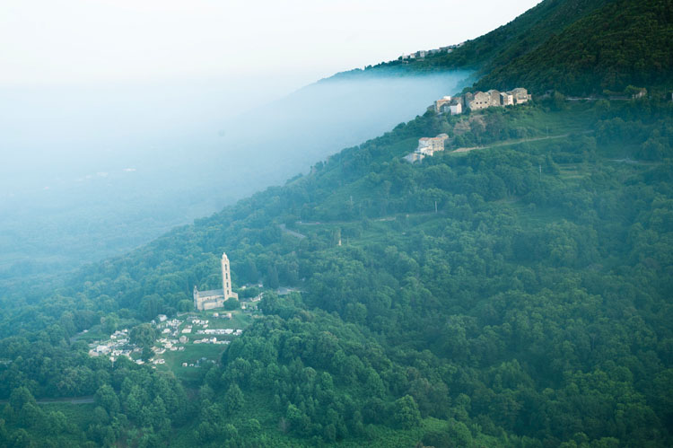 Vue d'ensemble du village de Mucchio et de l'église Saint-Nicolas depuis le nord