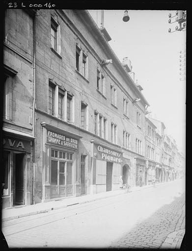 Façade avec devantures de boutiques (chaussures et fromages en gros), vue diagonale