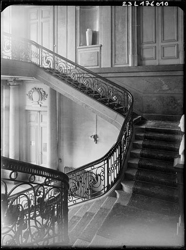 Intérieur : escalier vu entre deux étages et rampes en fer forgé