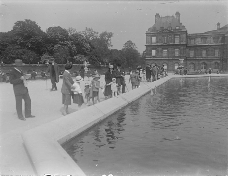 Marthe Antoine et Anne au bord du bassin au milieu des promeneurs, le palais en arrière-plan