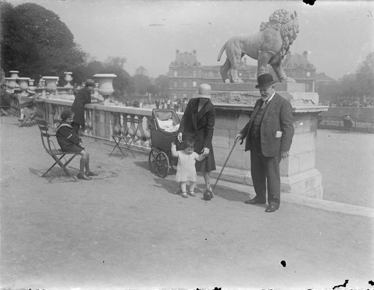 Jules et Marthe Antoine jouant avec Anne à la balle, statue de lion et palais en arrière-plan