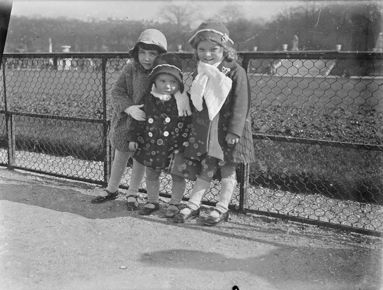 Anne, Agnès et une fillette en habits d'hiver posant devant un grillage