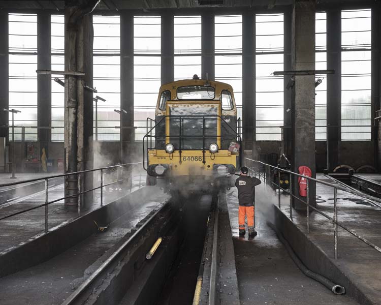 Homme nettoyant une locomotive dans un hangar