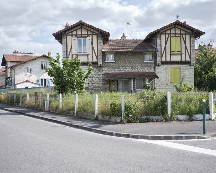 Depuis la rue, vue de deux maisons jumelées entourées d’un jardin