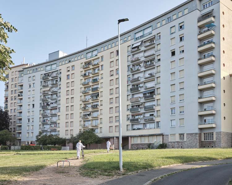 Vue d’ensemble de la façade animée de balcons, et du rez-de-chaussée paré de pierre