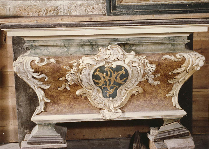 Autel galbé en bois sculpté de feuilles d'acanthe et d'un cartouche central au monogramme de la Vierge, bois peint en marbre feint