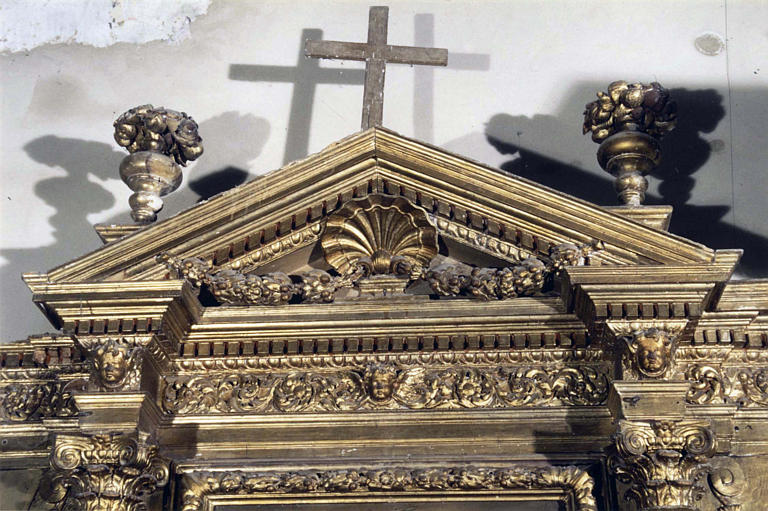 Retable : détail du fronton triangulaire sculpté d'une coquille et d'une guirlande de fleurs, flanqué de vases fleuris, bois sculpté, doré
