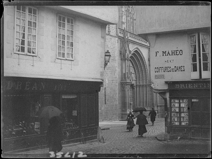 Portail de l'église, vue diagonale prise depuis la place Henry IV, vers le magasin de coiffure Mahéo