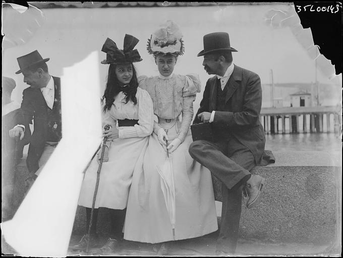 Promenade de bord de mer : groupe d'une fillette, d'une femme et d'un homme assis (partie de la prise de vue masquée par une bande en papier)